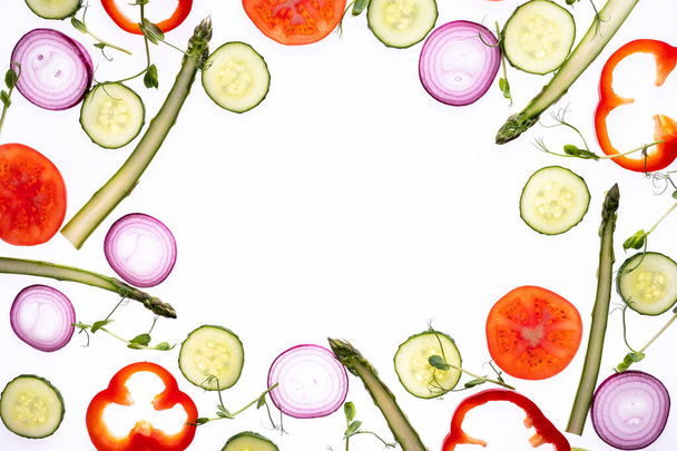 Modèle de mise en page créative faite de tranches de tomate oignon concombre asperges microvert poivre Pose plate. Concept de nourriture. Légumes isolés sur fond blanc. - Photo, image