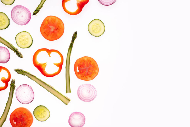 トマトスライス玉ねぎキュウリアスパラマイクログリーンペッパーフラットレイで作られた創造的なレイアウトパターン。食べ物の概念。白地に隔離された野菜. - 写真・画像