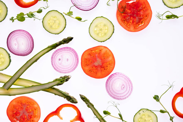 Creatief lay-out patroon gemaakt van tomatenschijfje ui komkommer asperges microgroene peper Flat lay. Voedselconcept. Groenten geïsoleerd op witte achtergrond. - Foto, afbeelding