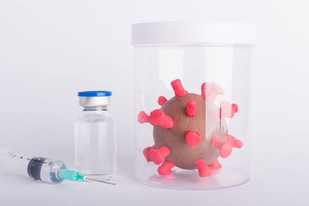 Крупним планом пластилінові клітини вірусних пляшок вакцина та шприц спалаху коронавірусу та коронавірусів грипу, студійний знімок ізольований на білому тлі, пандемія COVID-19 Медичне здоров'я
 - Фото, зображення