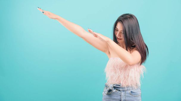 Asian happy portrait beautiful young woman standing smiling exercise Showing DAB dance gesture and looking to side isolated on blue background with copy space for text - Fotó, kép