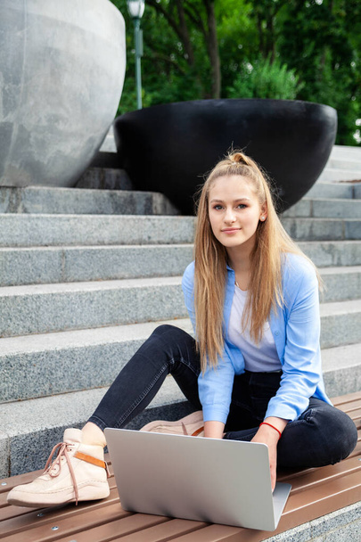 Elegante giovane donna europea che lavora su laptop, freelance, seduto nel parco, urban city street style, educazione online. - Foto, immagini