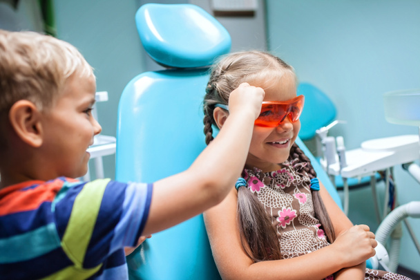 Due bambini che si divertono e indossano occhiali medici durante la loro visita allo studio dentistico, i due non hanno paura. Denti sani e trattamento indolore, concetto di odontoiatria pediatrica - Foto, immagini