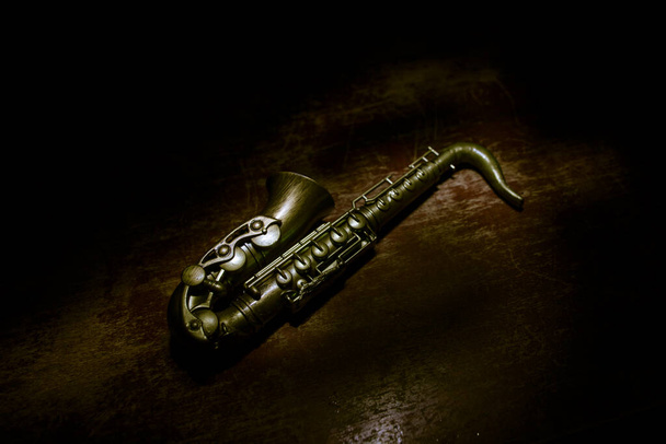 Концепция музыки. Саксофонный джазовый инструмент. Миниатюра из альто золота с цветным тонированным светом на туманном фоне. Саксофон музыкальный инструмент в низкой освещенности. Селективный фокус - Фото, изображение
