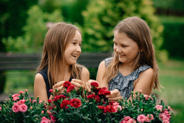 two happy girls in  park with flowers - Valokuva, kuva