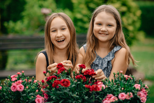 two happy girls in  park with flowers - Zdjęcie, obraz