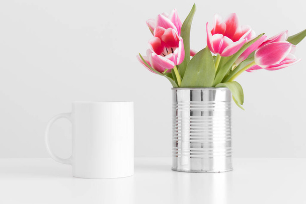 Mug mockup with pink tulips in a pot on a white table. - Фото, зображення