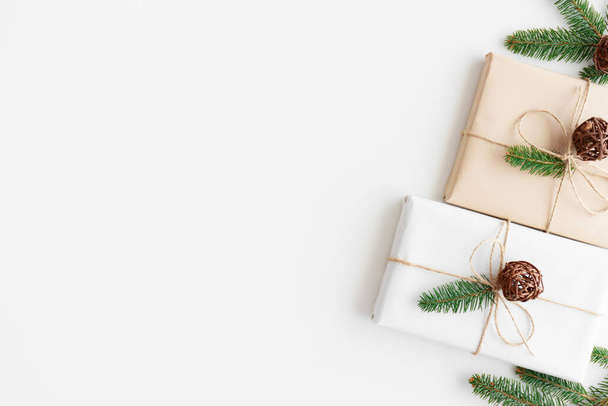 Cadeaux de Noël avec des feuilles de pin et ficelle sur une table blanche. Pose plate avec espace de copie vierge. - Photo, image