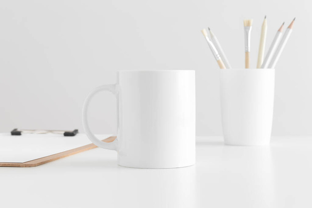 Taza de maqueta con accesorios de espacio de trabajo en una mesa blanca
. - Foto, Imagen