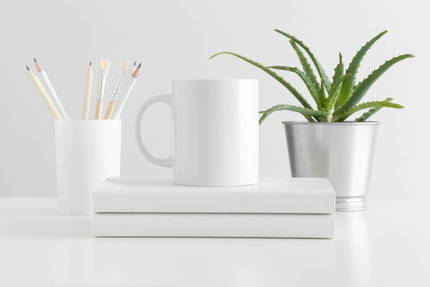 Mok mockup met werkruimte accessoires en een sappige plant op een witte tafel. - Foto, afbeelding