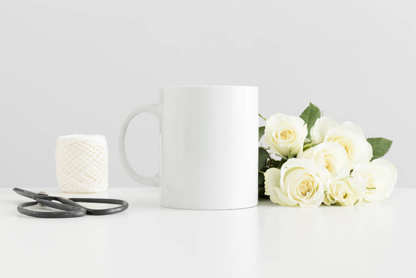 Mug mockup with a bouquet of roses and workspace accessories on a white table. - 写真・画像