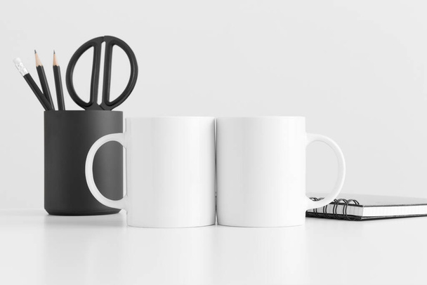 Two mugs mockup with workspace accessories on a white table. - 写真・画像