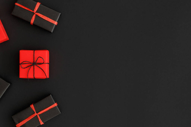 Red and black christmas gifts on a black background. Flat lay with blank copy space. - 写真・画像