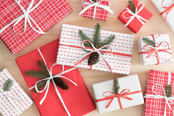 Múltiples regalos de Navidad coloridos con conos de pino y hojas en una mesa de madera
. - Foto, imagen