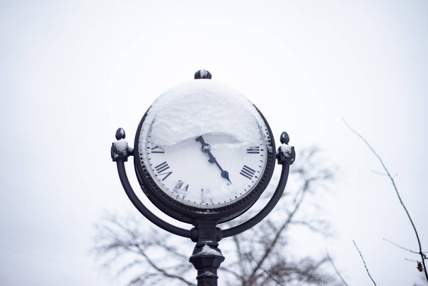 inverno, un pilastro stradale con un orologio sotto la neve bianca d'argento - Foto, immagini