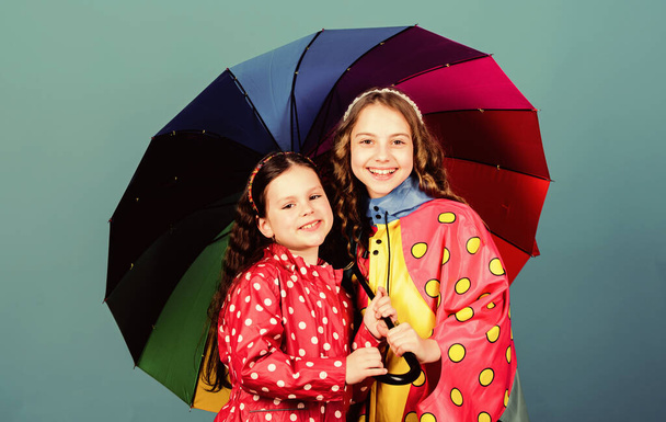 cheerful hipster children, sisterhood. autumn fashion. happy little girls with colorful umbrella. rain protection. Rainbow. family bonds. Little girls in raincoat. Going crazy together - Фото, зображення
