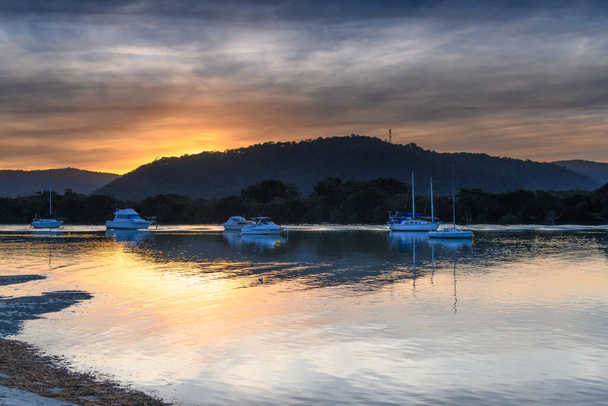 Woy Woy, NSW, Australia - 18 July 2020: Sunset waterscape with soft high clouds at Woy Woy on the Central Coast, NSW, Australia. - 写真・画像