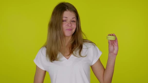 Nainen nostaa kätensä keltaisella macaronilla, osoittaa vastenmielisyyttä, kättelee - Materiaali, video