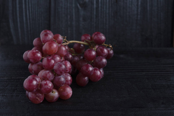 Ramo de uva roja aislado sobre fondo de madera oscura
 - Foto, imagen