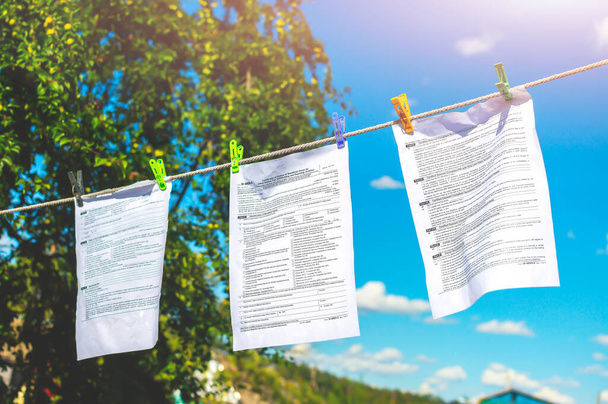The documents tax forms were washed and dried in the open air by hanging from a clothesline. Concepts of money laundering, legalization of income, concealment of income, tax evasion. - Photo, Image