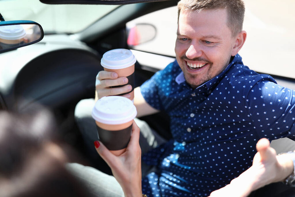 コーヒーを持っていて車で笑っている女性と男 - 写真・画像