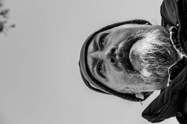 negro y blanco primer plano, disparado desde abajo de hombre de mediana edad con barba, sombrero y mirada intensa
 - Foto, Imagen
