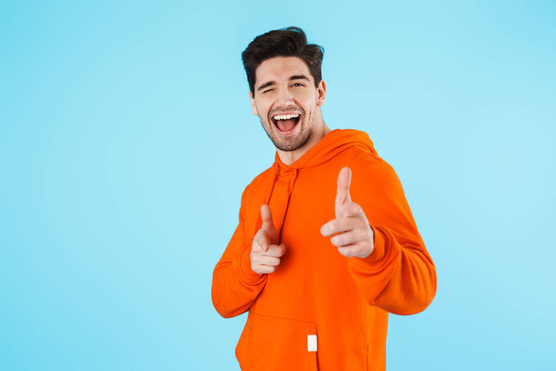 Image of a happy young bristle man isolated over blue wall background pointing to you. - Photo, Image