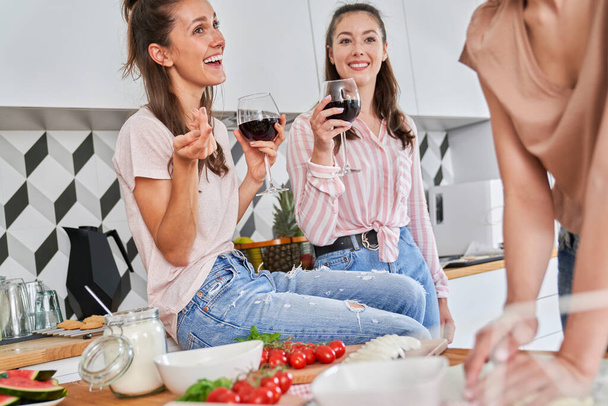 Tres amigos dando una fiesta en casa con vino y pizza
 - Foto, imagen