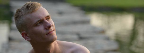 Portrait of young man with blond hair shirtless at the park outdoors - Photo, Image