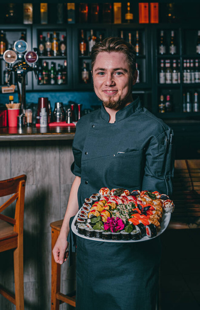 Portrait of chef in cafe showing plate with sushi - Fotografie, Obrázek