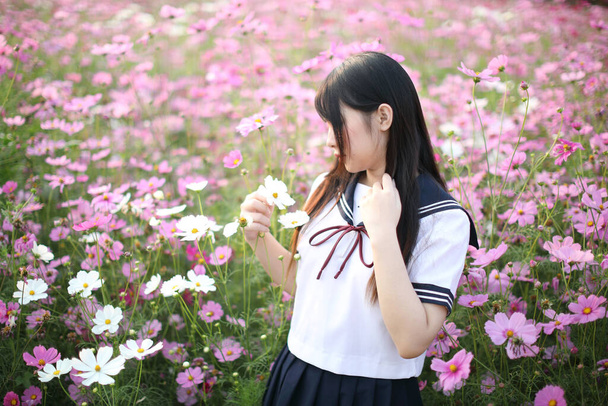 Porträt einer japanischen Schulmädchenuniform mit rosa Kosmos-Blume  - Foto, Bild