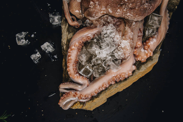 Whole raw octopus on a stone table - Zdjęcie, obraz