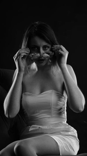 όμορφη γυναίκα με σύντομη ακούσει στο φόρεμα ποζάρουν σε σκούρο φόντο στούντιο  - Φωτογραφία, εικόνα