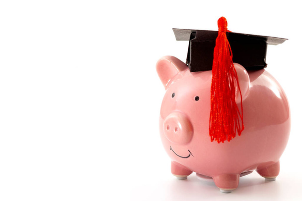 College education costs, tuition financial aid, university graduate economic cost concept theme with close up on piggy bank wearing a graduation cap isolated on white background with copy space - Photo, Image