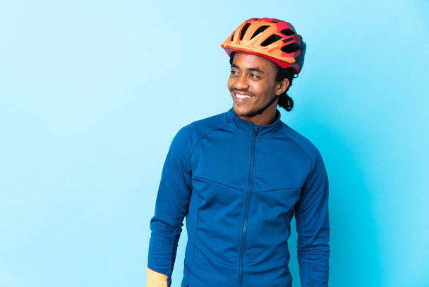 Młody rowerzysta z warkoczami na odosobnionym tle spoglądający w bok i uśmiechnięty - Zdjęcie, obraz