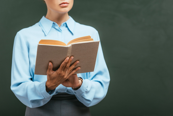 cropped view of teacher reading book while standing near chalkboard  - Φωτογραφία, εικόνα