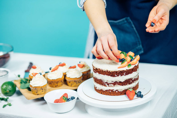 Cropped image of woman hands decorating cupcakes with berries - Foto, afbeelding