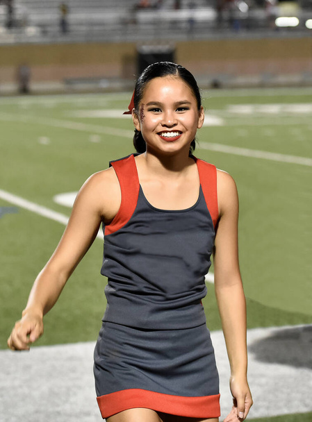 Cute Asian American Cheerleader performing at a high school football game - Photo, Image