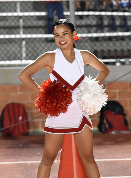 Linda animadora asiática americana actuando en un partido de fútbol de la escuela secundaria
 - Foto, Imagen