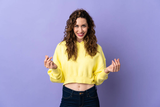 Young caucasian woman isolated on purple background making money gesture - Photo, Image