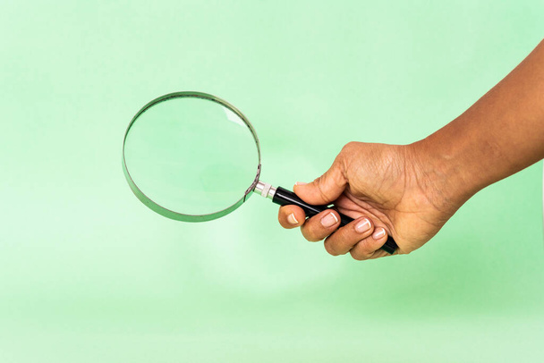 magnifying glass in hand against color background  - Photo, Image