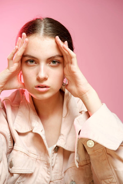 A girl in a pink denim shows different emotions and poses on a pink background. - Фото, изображение
