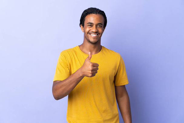 Jonge Afro-Amerikaanse man met vlechten man geïsoleerd op paarse achtergrond geven van een duim omhoog gebaar - Foto, afbeelding
