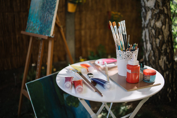 Paint tubes and brushes on table outdoor - 写真・画像