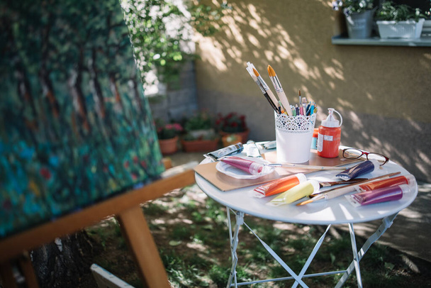 Table with paint tubes and brushes outdoor - Photo, Image