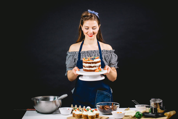 Pin-up styled woman presenting cake - Фото, зображення