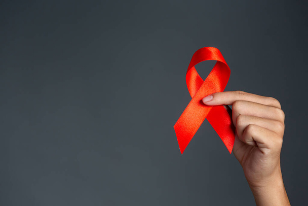 Une main de femme tenant un ruban rouge Concept de sensibilisation au VIH Journée mondiale du sida et Journée mondiale de la santé sexuelle. - Photo, image