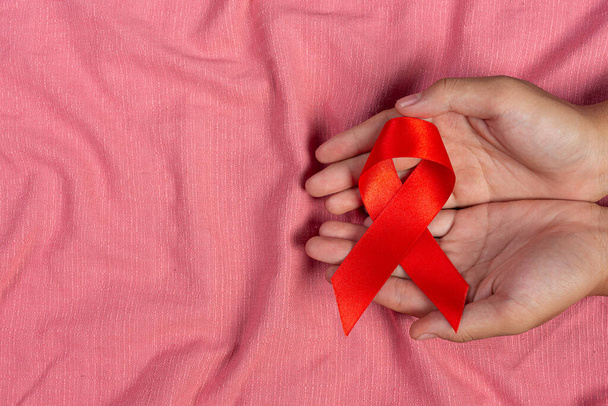 Woman hand holding red ribbon HIV awareness concept World AIDS Day and World Sexual Health Day. - Photo, image