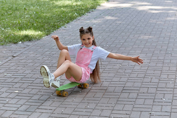 The girl is actively involved in sports and rides a skateboard. - Zdjęcie, obraz