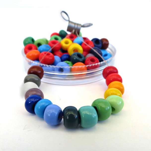 Transparent bowl of colorful glass beads for crafting and jewelry making. DIY kit, crafting with children. Hobby, handmade jewelery. - Photo, Image